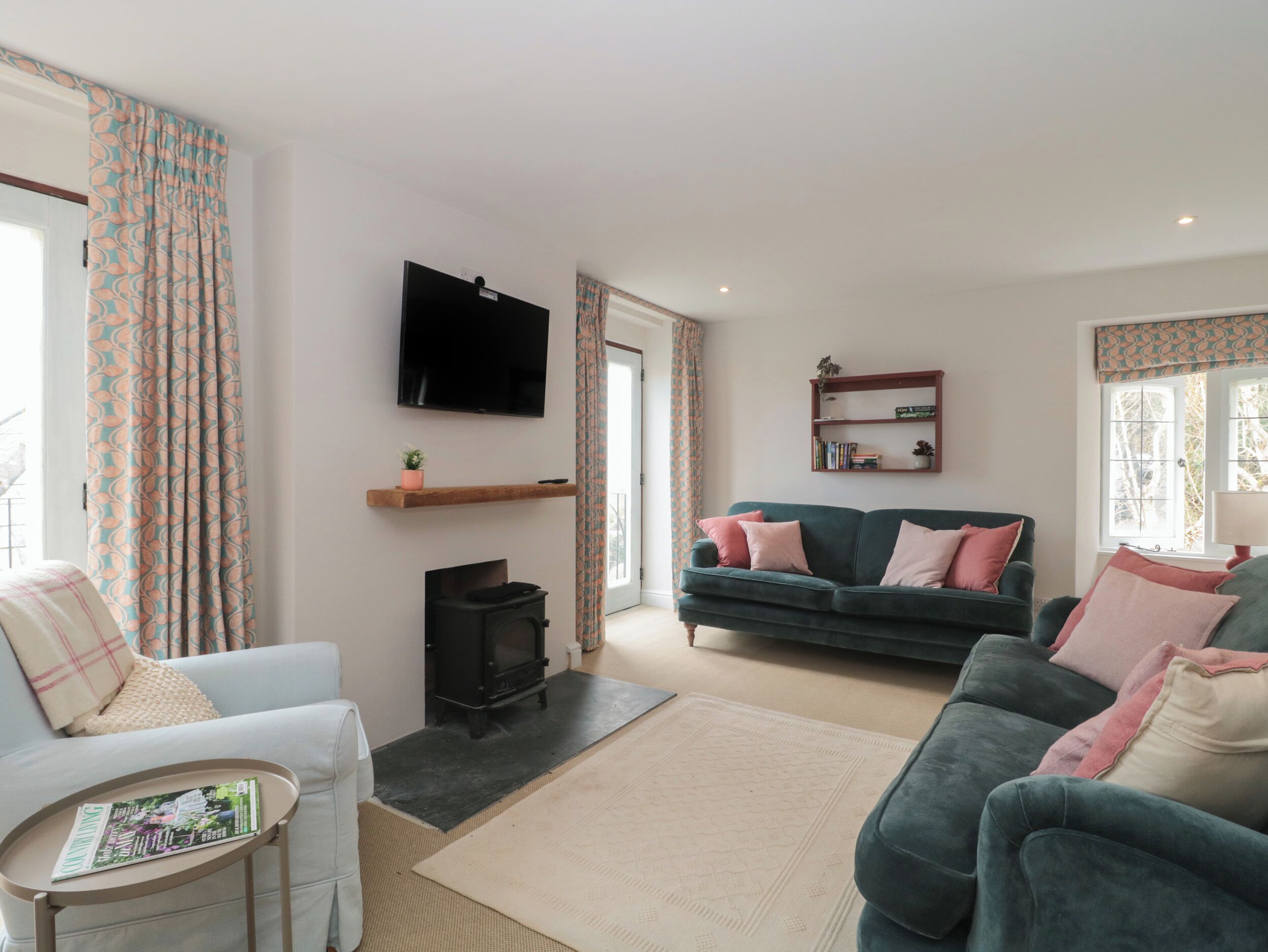 Una sala de estar con sofá, sillón, televisor, chimenea y estantería.
