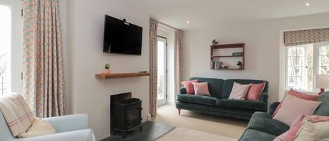 Una sala de estar con sofá, sillón, televisor, chimenea y estantería.