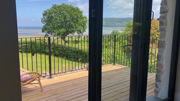Een balkon met uitzicht op een gazon, een boom en een verafgelegen landschap.