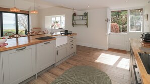 Een moderne keuken met houten aanrechtbladen, witte kasten en een groot raam met uitzicht op een tuin.