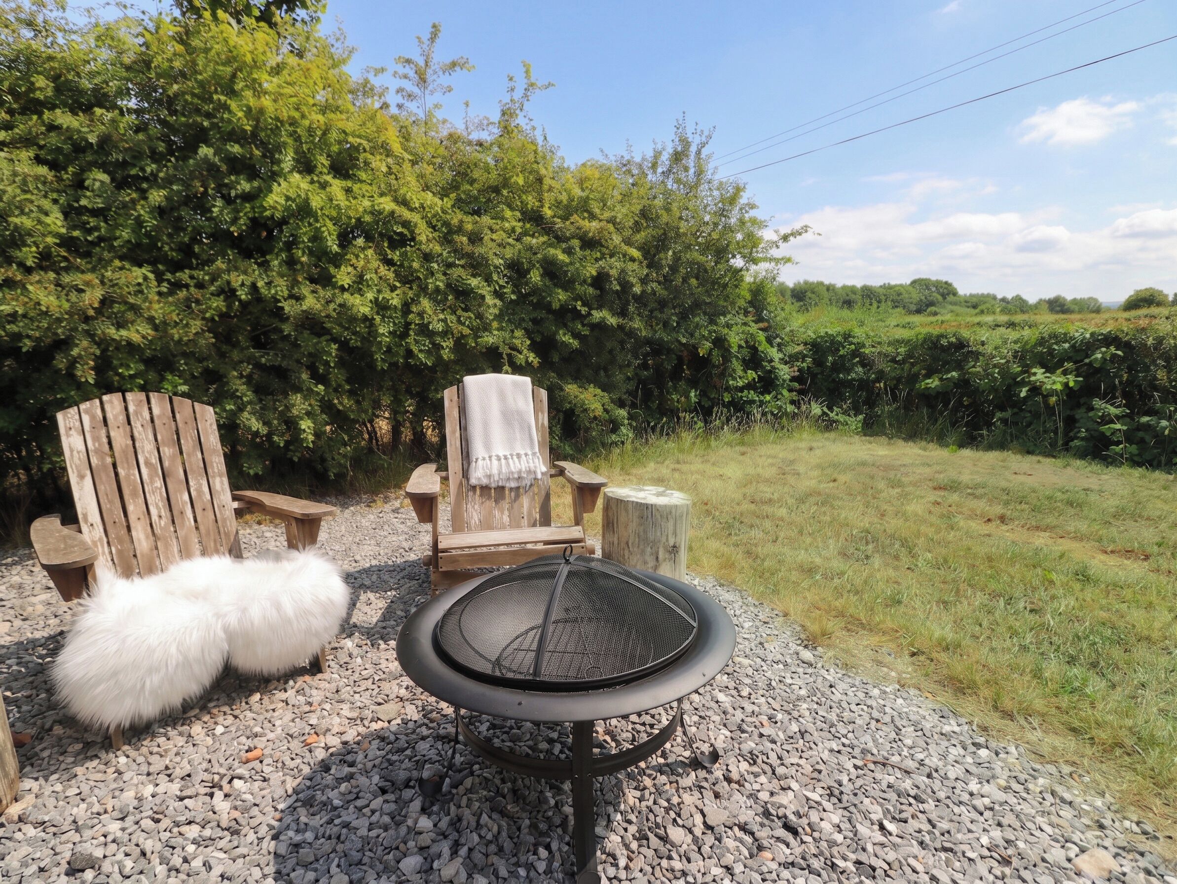 A grill with a mesh screen, two wooden chairs, a white fluffy object, and a gravel path.