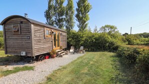 Une cabane en bois avec un petit porche et un chemin de gravier menant à l’entrée.