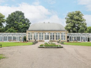 A large conservatory with a central dome and multiple glass-paneled wings, surrounded by a gravel courtyard and flower beds. - 56 Riverdale Road (Sheffield)