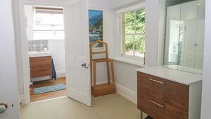 Ein modernes Badezimmer mit Dusche, einer Holztür und einem Fenster mit Blick auf Grünflächen.