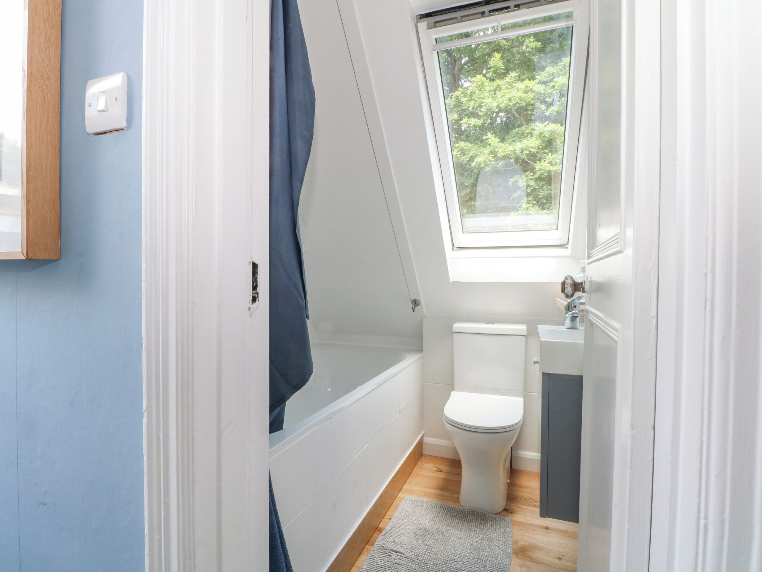 A small bathroom with a toilet, a bathtub, and a window.
