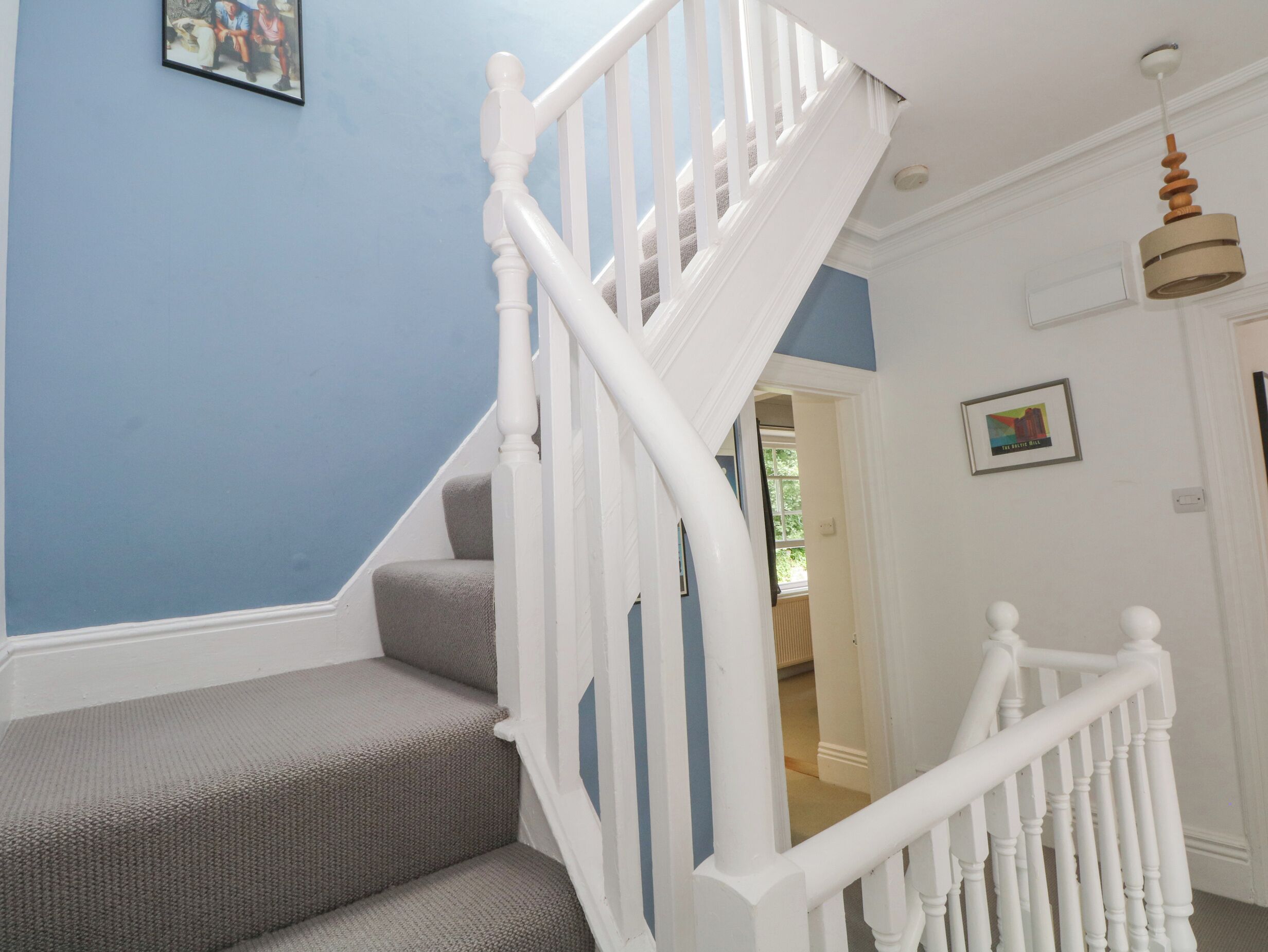 A staircase with white balusters and a grey carpeted landing.