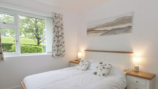 A bedroom with a bed, two bedside tables, a nightstand, a window with curtains, and a wall-mounted painting. - Belle Vue (Stoke-on-Trent)