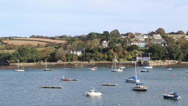 Un village côtier où des bateaux sont amarrés le long de la plage, avec des maisons en arrière-plan.