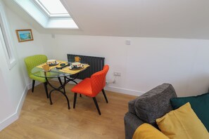 A compact living space with a dining area, a sofa, and a radiator. - Cuckoo's Rest (Penryn)