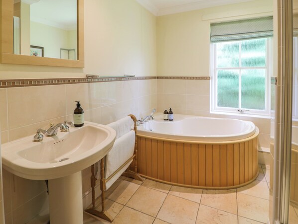A bathroom with a freestanding bathtub, a sink, and a mirror.