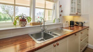 Een keuken met een houten aanrecht, een roestvrijstalen spoelbak en witte kastjes.
