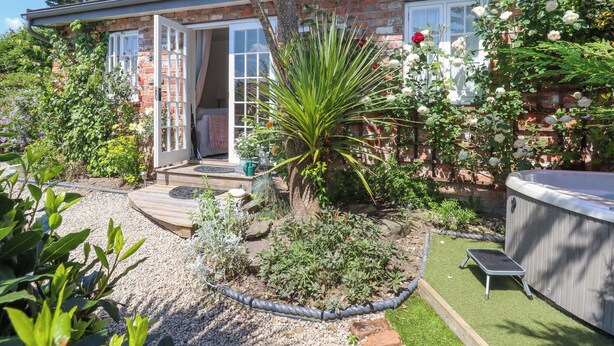 A brick house with a garden, a patio, and a red umbrella. - Sunset Cottage (Barnstaple)