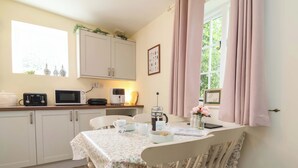 A cozy kitchen with white cabinets, a microwave, a toaster, and a coffee maker. - Sunset Cottage (Barnstaple)