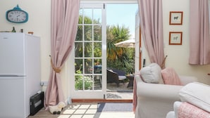 A cozy living room with a white sofa, a white refrigerator, and a clock on the wall. - Sunset Cottage (Barnstaple)