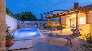 Un espace piscine privatif avec des chaises longues et une pergola.