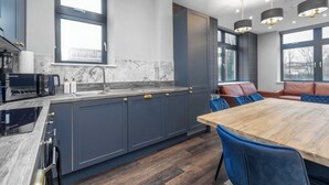 A modern kitchen with dark cabinetry, a wooden dining table, and blue chairs.