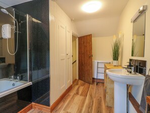 A bathroom with a glass-enclosed shower, a white sink, and a wooden door. - Rock Cottage (Matlock)
