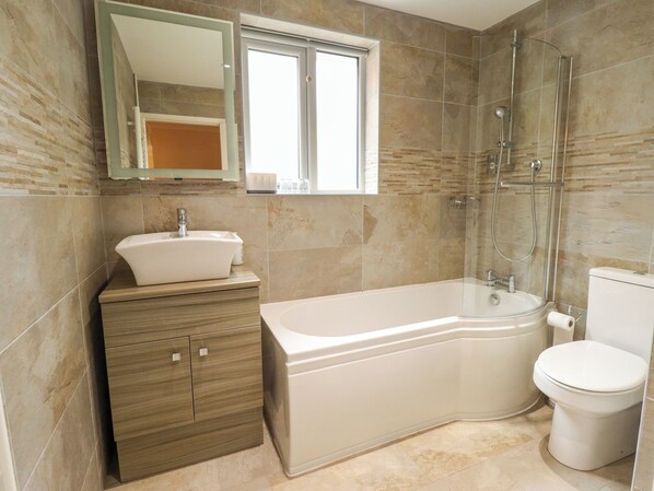 A bathroom with a sink, vanity, bathtub, and toilet. - Number 16 (Woodhall Spa)