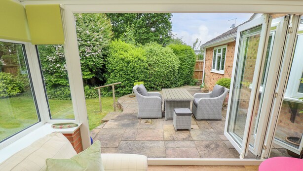 A patio with wicker furniture, a wooden table, and a cushioned sofa. - Number 16 (Woodhall Spa)