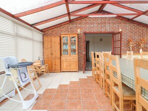 A covered patio with a brick wall, wooden furniture, and a radiator. - Stensonhill Lodge (Derby)