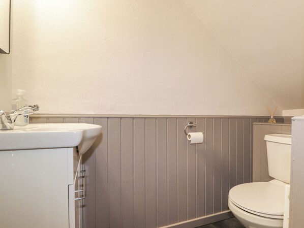 A bathroom with a white sink, a toilet, and a toilet paper holder. - Garry Isle (Inverness)