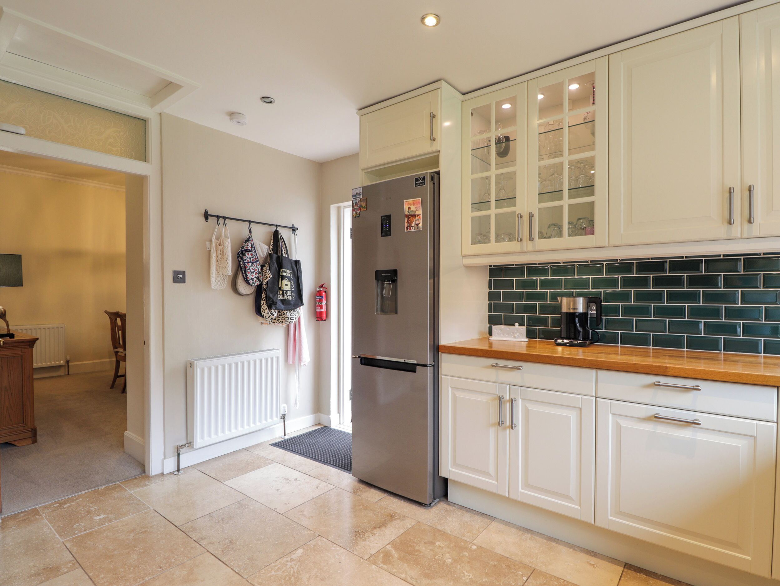 Una cocina moderna con armarios blancos, un refrigerador de acero inoxidable y un salpicadero de azulejos verdes.