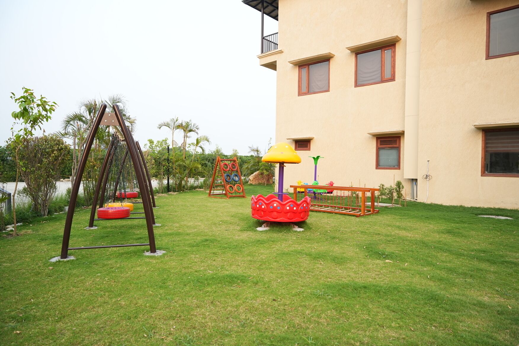 A grassy outdoor area with playground equipment including swings, a slide, and a climbing structure.