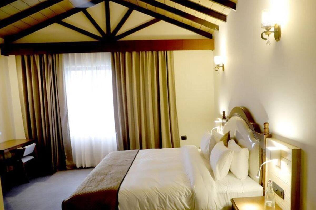 Une chambre d’hôtel avec un grand lit, un bureau et une table de chevet avec une lampe.