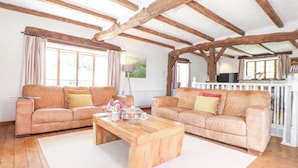 A spacious living room with two leather sofas, a wooden coffee table, and a white rug. - Skiber Coombe (Callington)