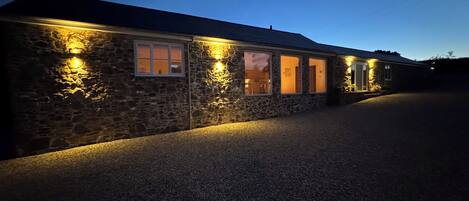 A stone building with multiple windows illuminated by warm lighting.