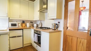 A compact kitchen with white cabinets, a microwave, a stove, and a sink. - 4 Pembroke Street (Skipton)