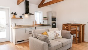 Eine moderne Küche mit weißen Schränken, einer Holzbalkendecke und einem Essbereich mit einem Holztisch und Stühlen.