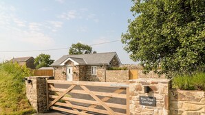 Ein Steinhaus mit einem Holztor, einem Schild mit der Aufschrift 'Pear Tree Cottage' und einem gepflasterten Weg.