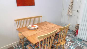 Un comedor con una mesa y sillas de madera, una pila de platos y un piso con baldosas coloridas.