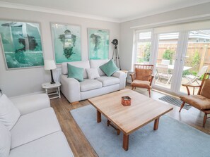 A modern living room with a white sofa, a wooden coffee table, and a large window with a view of the backyard. - Turnstone (Chathill)