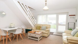 Un salon moderne comprenant un coin repas, un escalier et une vue sur l’extérieur.