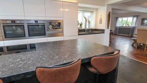 Una cocina moderna con electrodomésticos integrados, una isla central con taburetes y vistas al área de comedor.