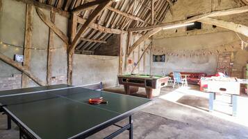 A spacious indoor area with a ping pong table, a pool table, and a foosball table.
