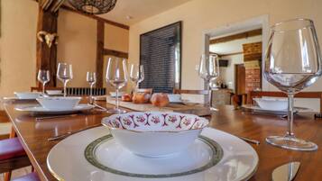 A dining table set with plates, bowls, and wine glasses, with a rustic wooden table and a decorative ceiling light.