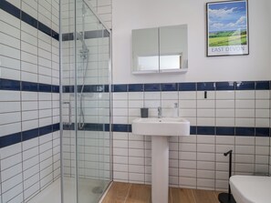 A bathroom with a glass-enclosed shower, a white sink, and a mirror above it. - Pit Close (Honiton)