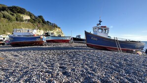 Des bateaux étaient amarrés sur une plage de galets, avec une falaise en arrière-plan.
