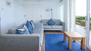 A modern living room with two grey sofas, a wooden coffee table, and a blue rug. - Ael Y Don (Harlech)