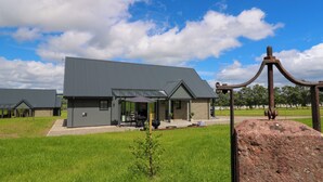 A modern building with a flat roof, a covered patio area, and a stone facade. - Bramble Cottage (Blairgowrie)
