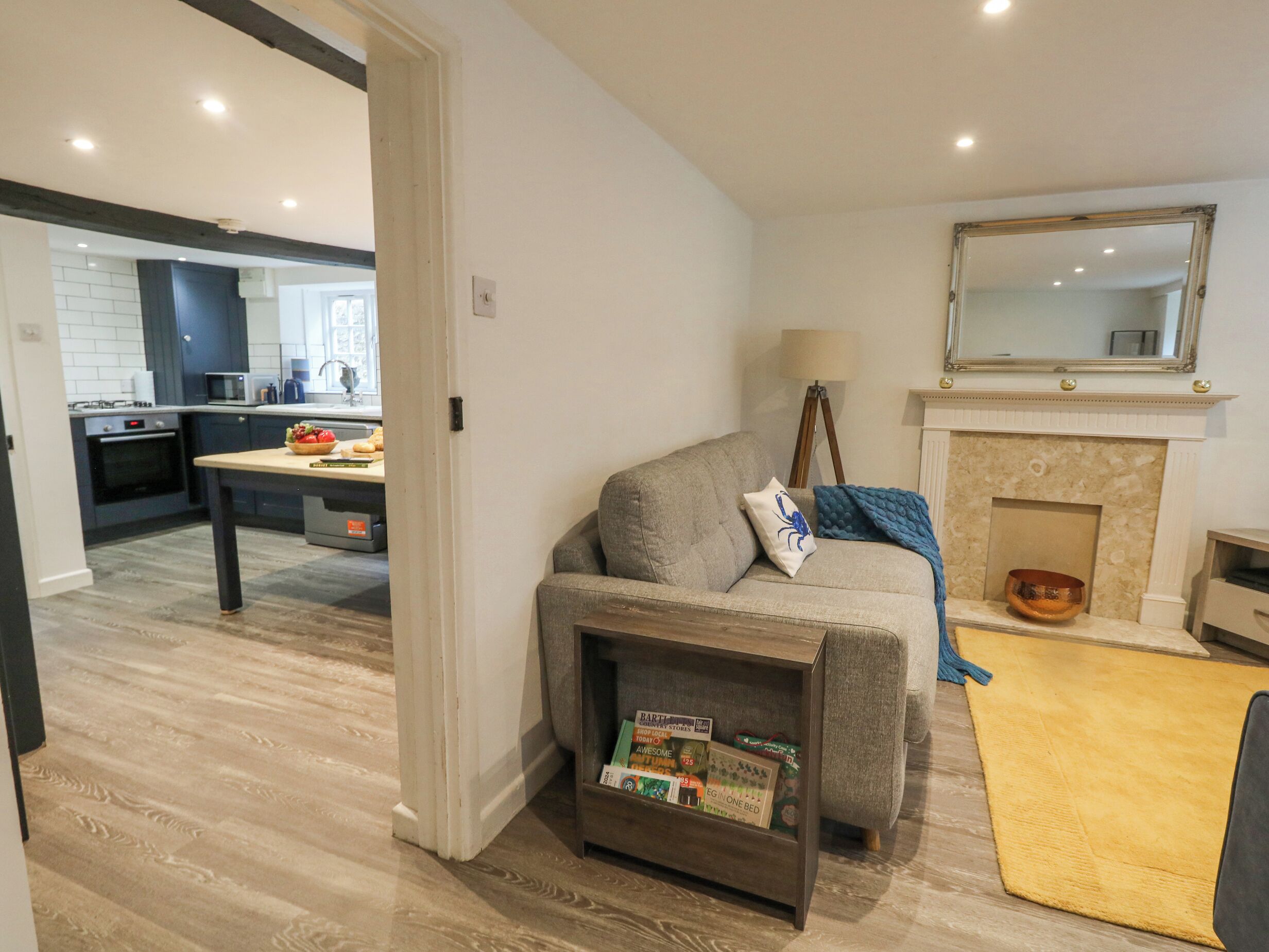 A modern living room with a grey sofa, a small side table, a yellow rug, and a fireplace.