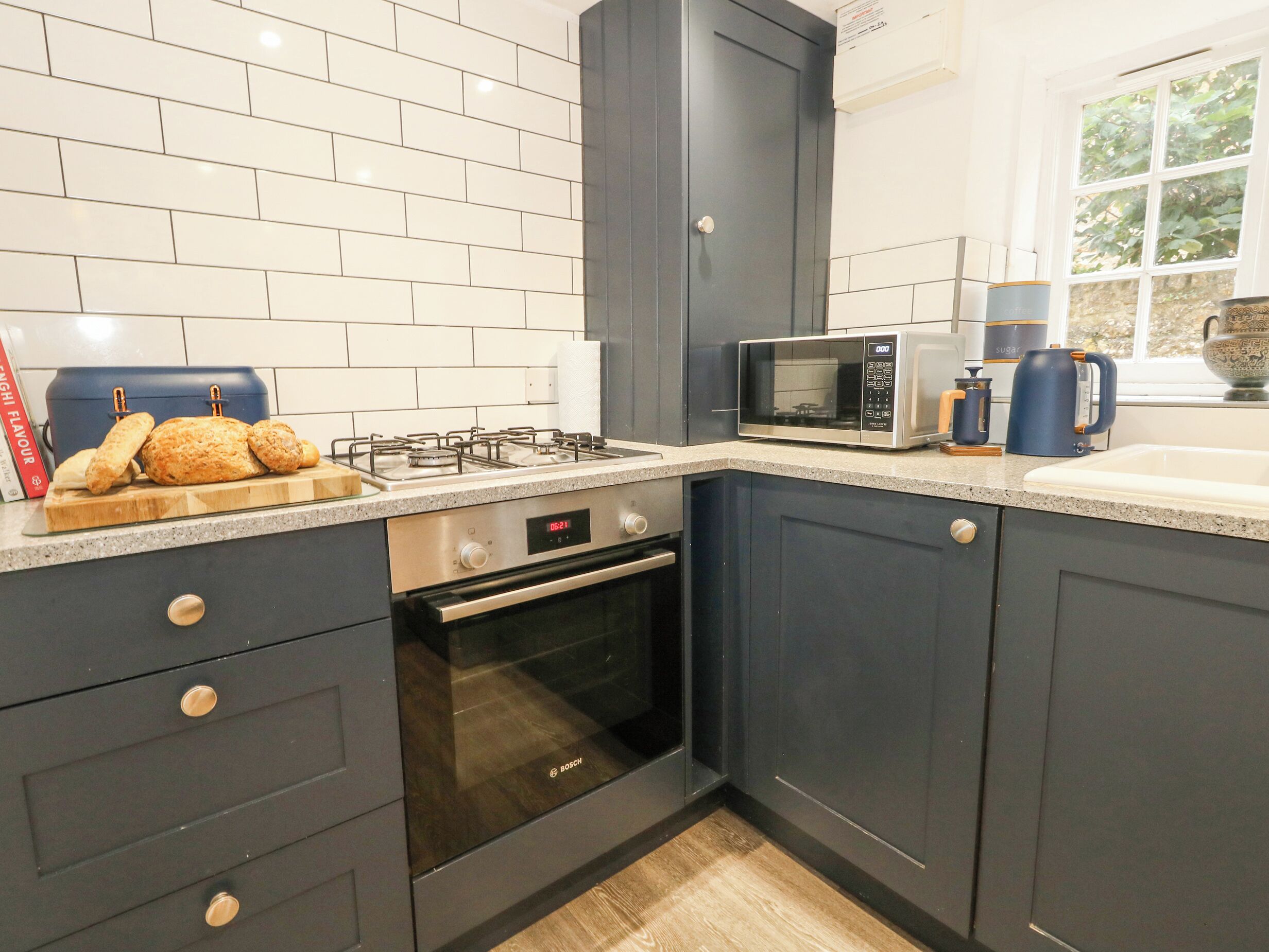Uma cozinha moderna com armários escuros, um forno Bosch, micro-ondas e fogão a gás.