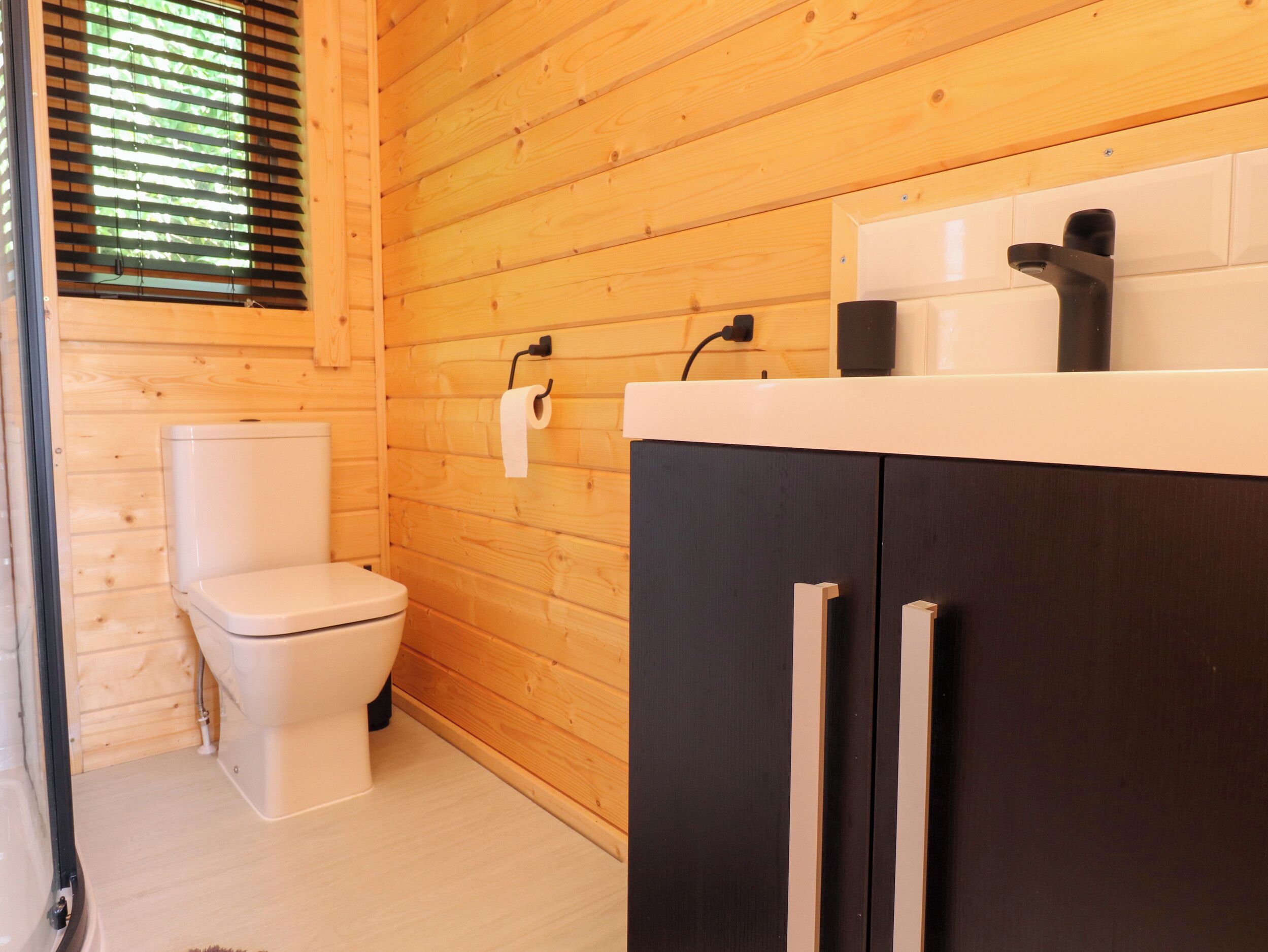 A wooden-paneled bathroom with a toilet, a sink, and a cabinet.