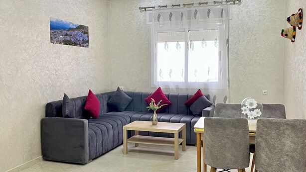 Ein Wohnzimmer mit grauem Sofa, einem Holztisch und grauen Sesseln.