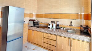 Eine moderne Küche mit Edelstahlkühlschrank, Holzschränken, einer Granit Arbeitsplatte und einer gefliesten Spritzwand.