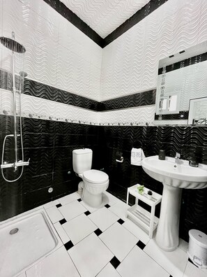 Een badkamer met toilet, wastafel, douche en betegelde vloer.