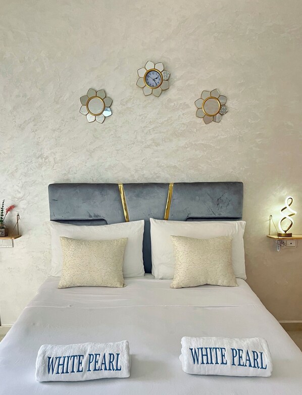 Una cama con dos almohadas, un cabecero y dos relojes de pared.
